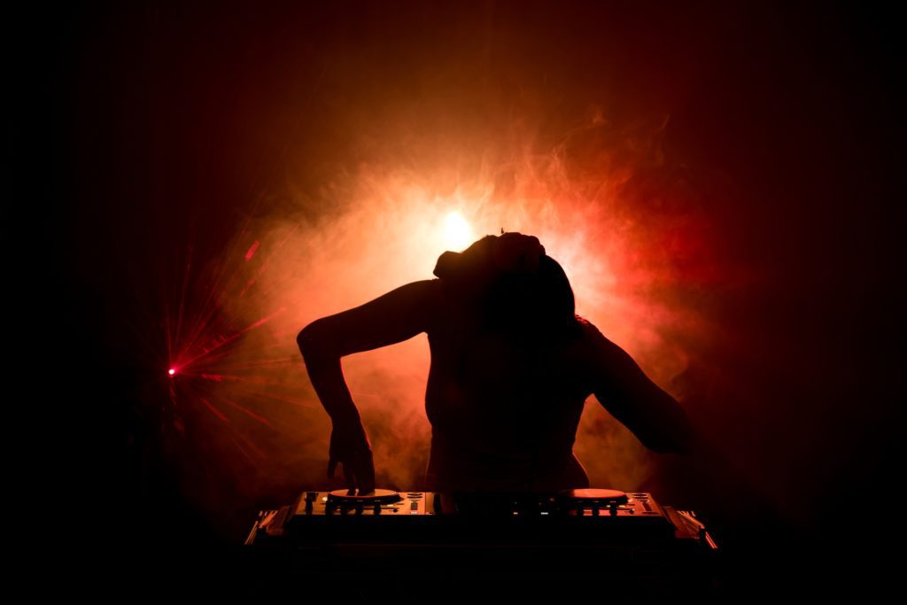 a silhouette of a woman playing music on a dj table