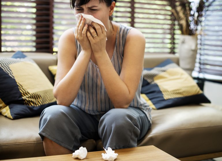 Sick woman sneezing into tissue