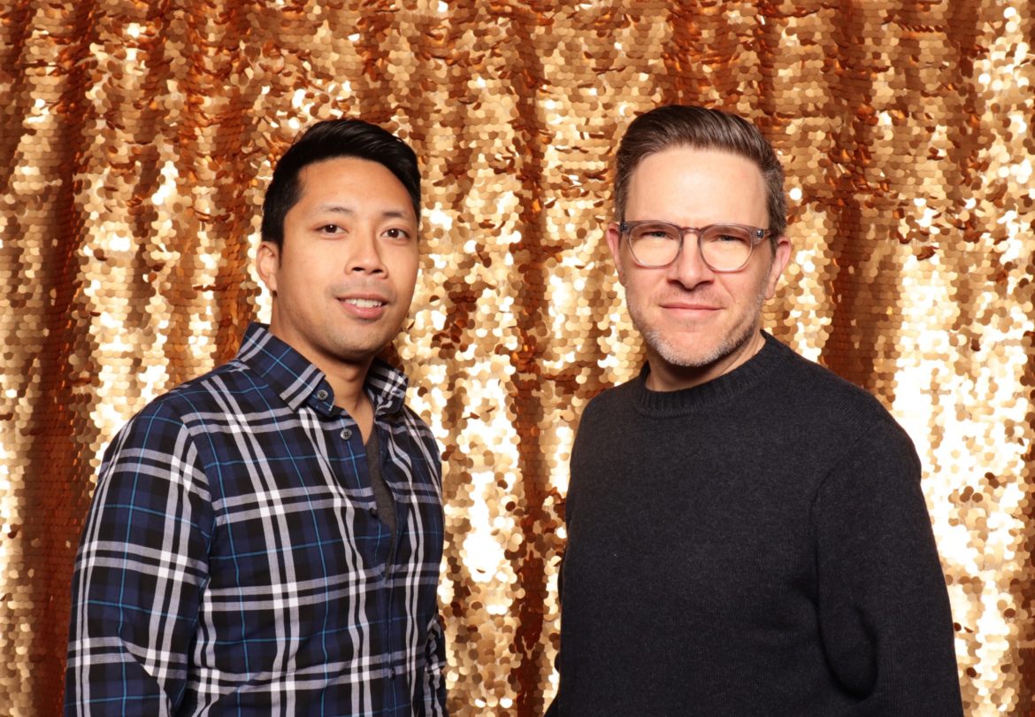 two men standing in front of a gold curtain