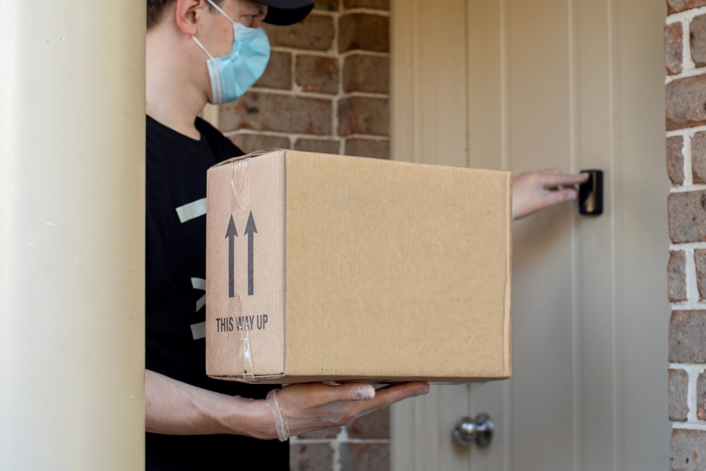 a person wearing a mask and gloves holding a box