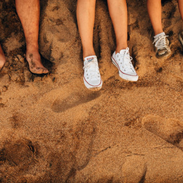 a group of people's feet in the sand