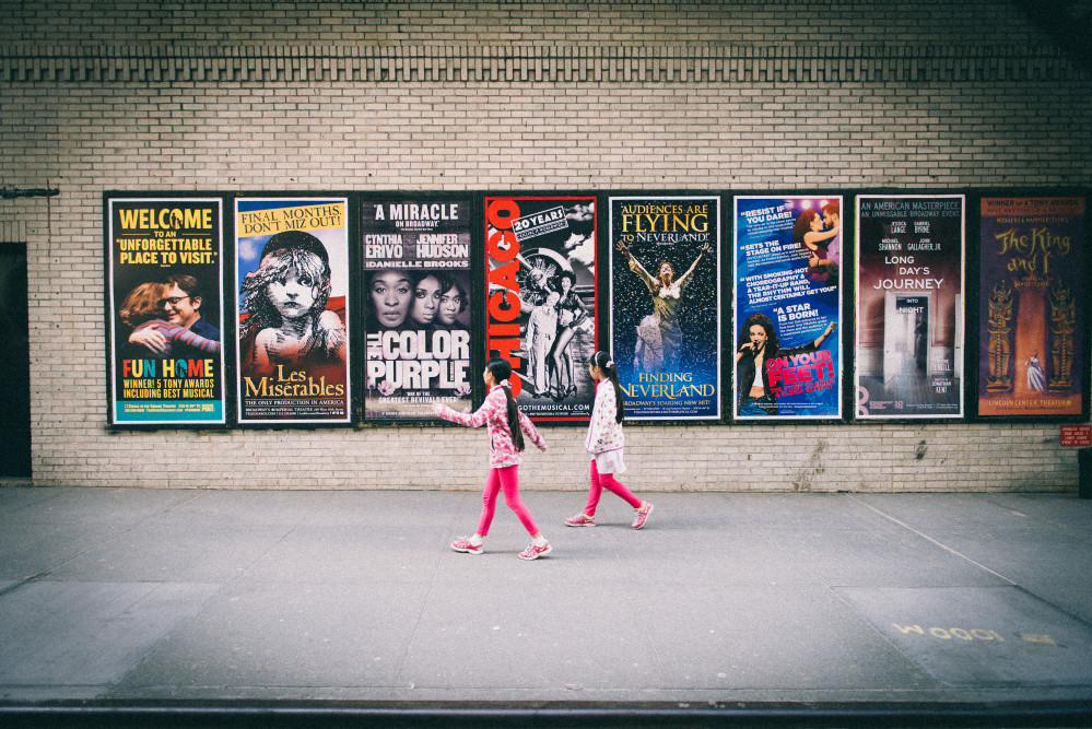 two girls walking in front of posters