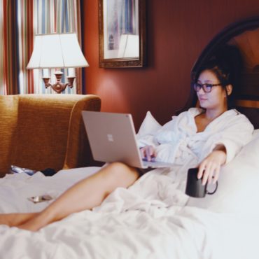 a woman in a bathrobe using a laptop in bed