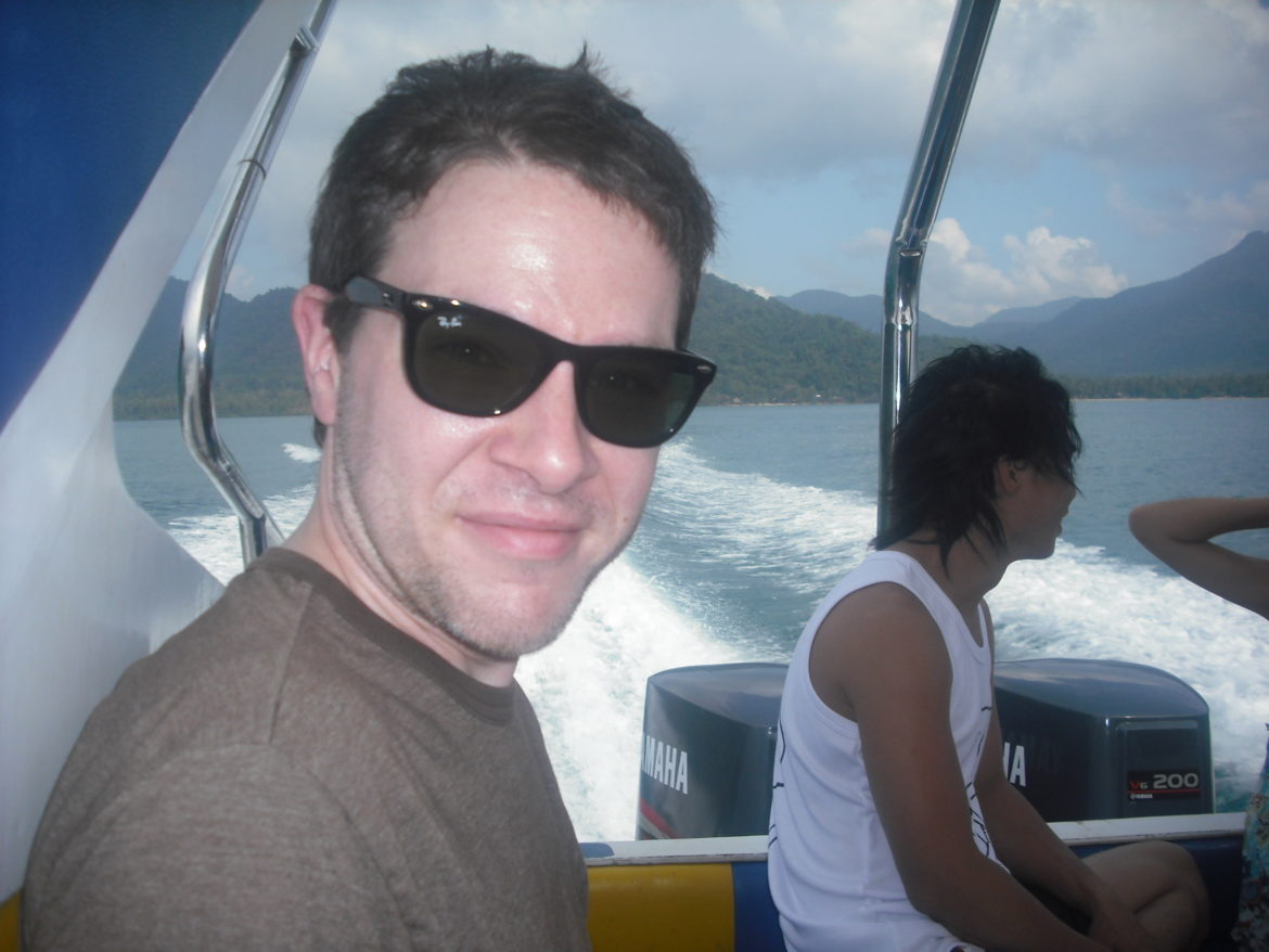 a man in sunglasses taking a selfie on a boat