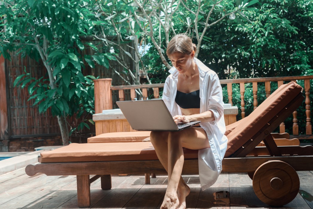 a woman sitting on a lounge chair using a laptop