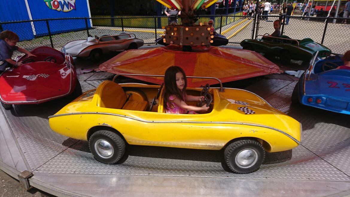 a girl driving a small yellow car