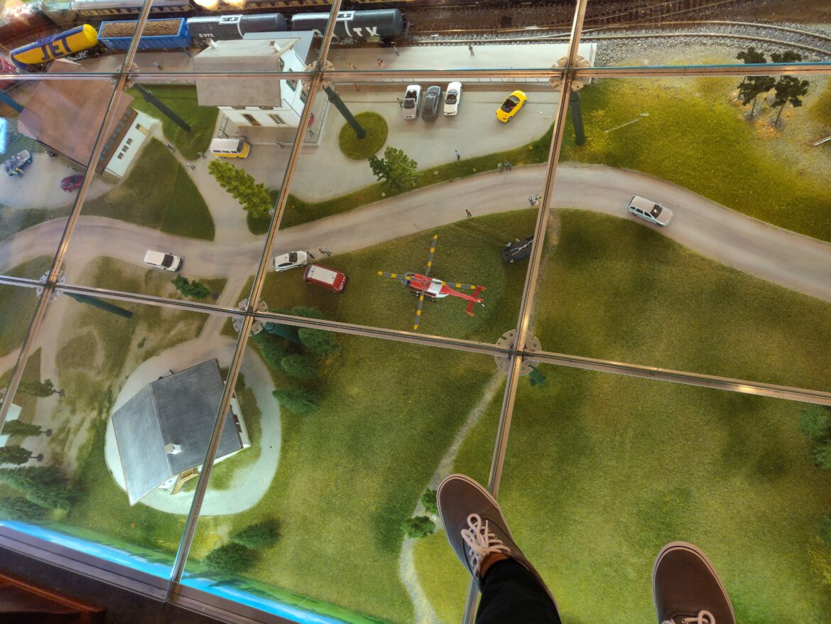 a person's feet on a glass floor looking down at a model of a city