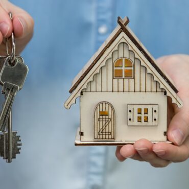 a person holding a small house and keys