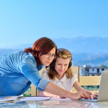Mother helping her daughter to a schoolgirl with online studies
