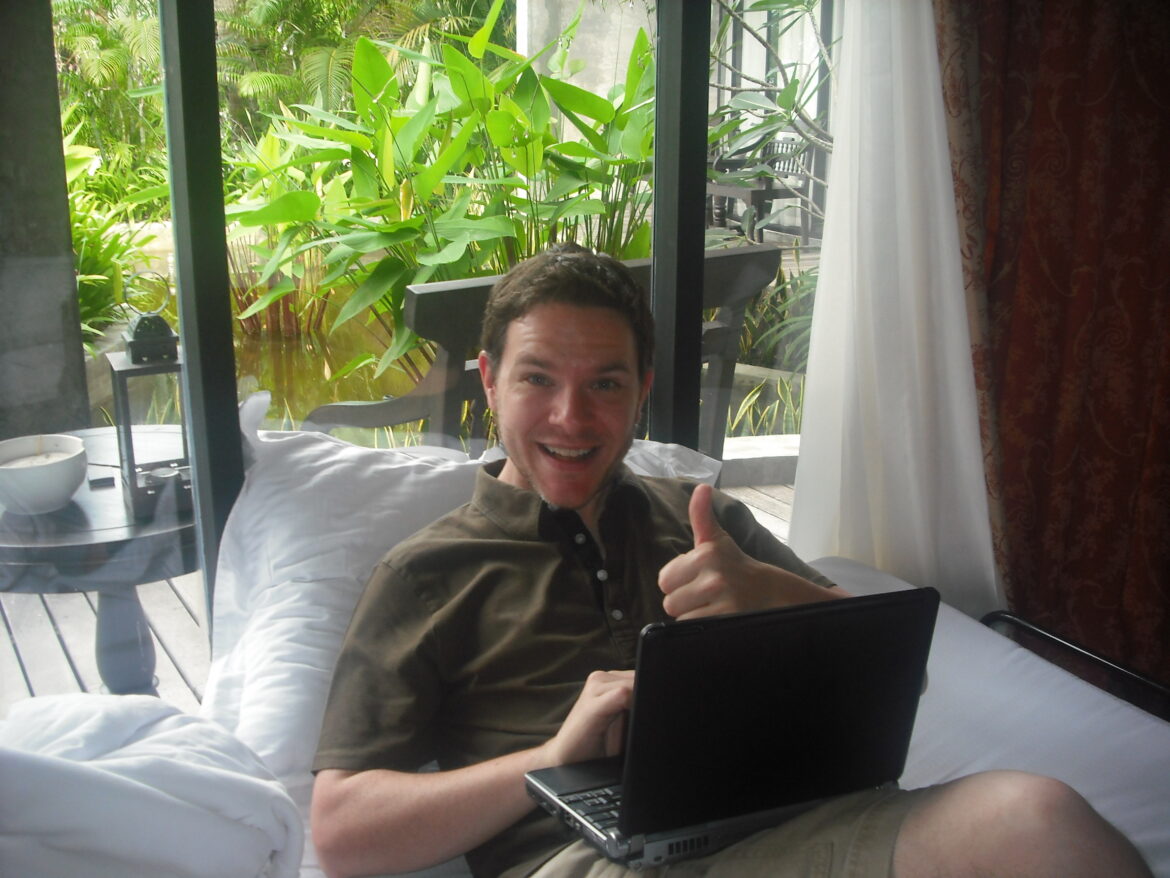 a man sitting on a bed with a laptop