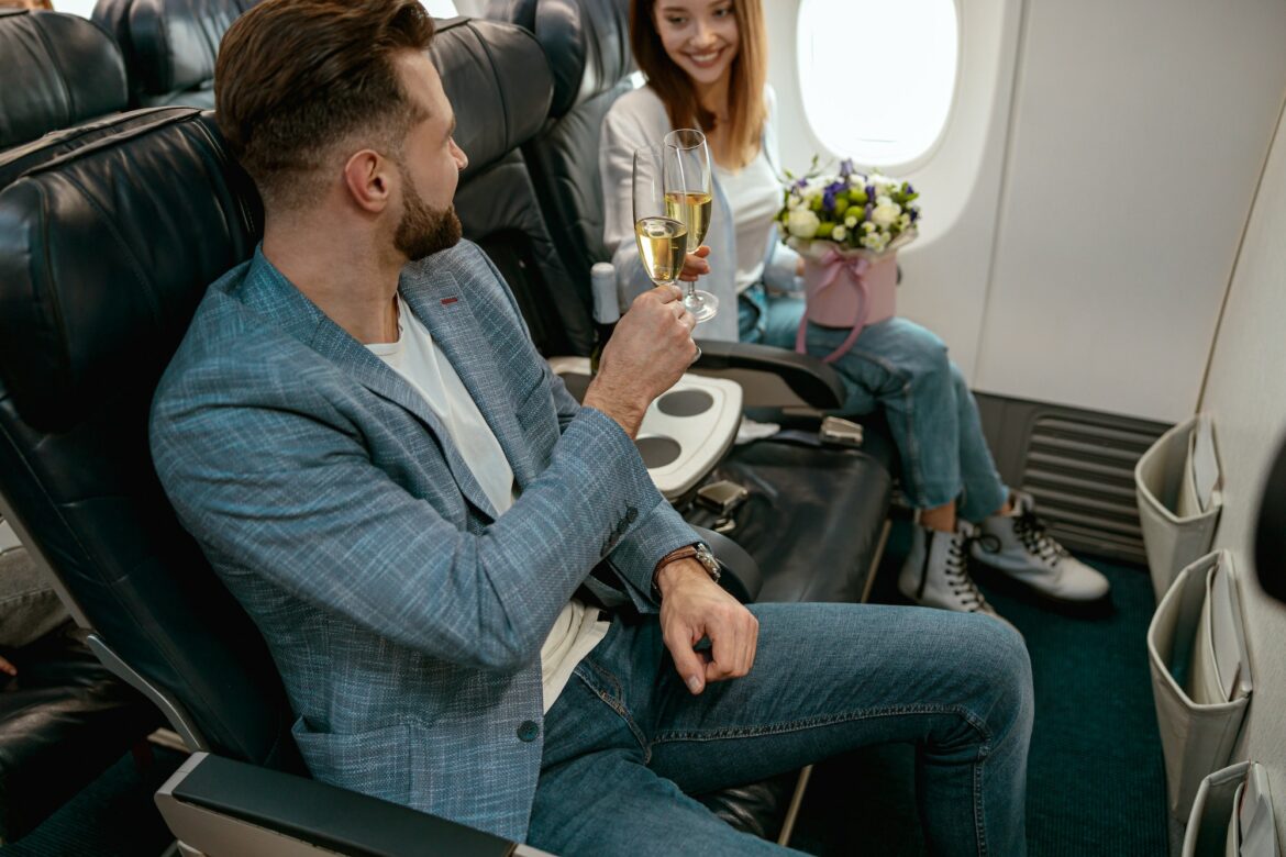 Cheerful woman and man toasting with champagne in plane