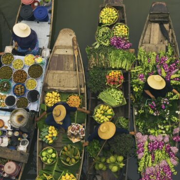 Aerial view of a floating market on a canal in Bangkok, local boats laden with fresh food, moored