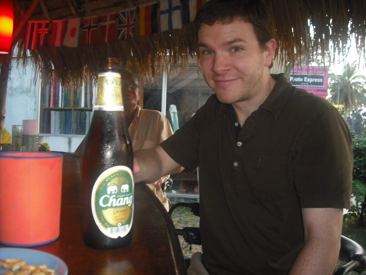 a man sitting at a table with a bottle of beer