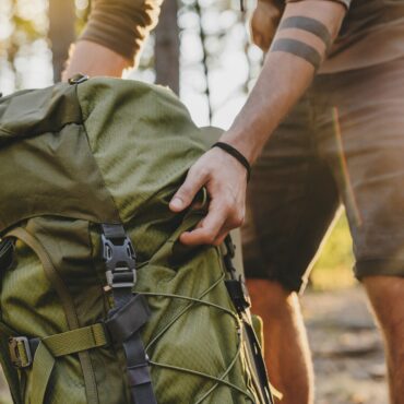 Close up of male hiker holding his camping backpack. Traveler