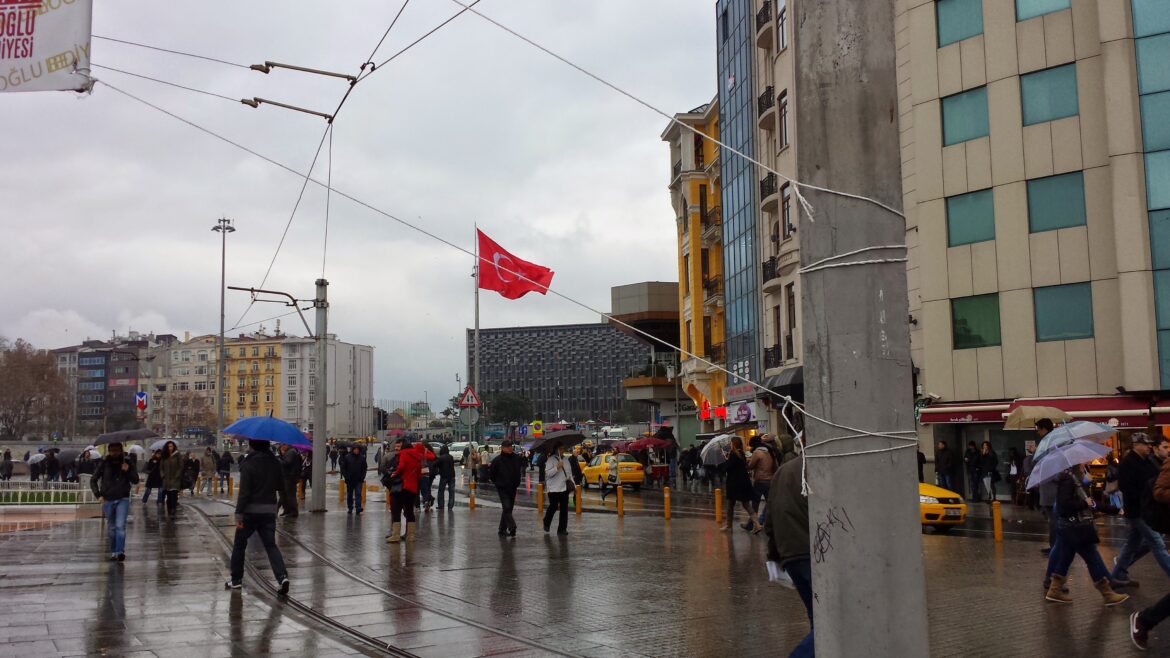 a group of people walking on a street with a flag on a pole