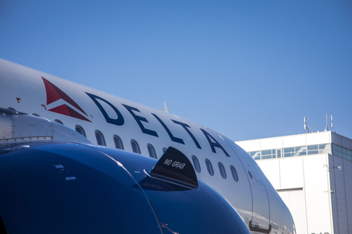 The image shows a close-up of a Delta Air Lines airplane. The Delta logo and name are prominently displayed on the side of the aircraft. Configured with Delta A321neo First Class
