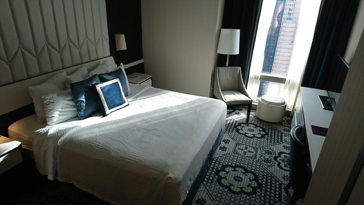 a bed with pillows and a chair in a room is a lighter version of what you get with our hotel room upgrade tips