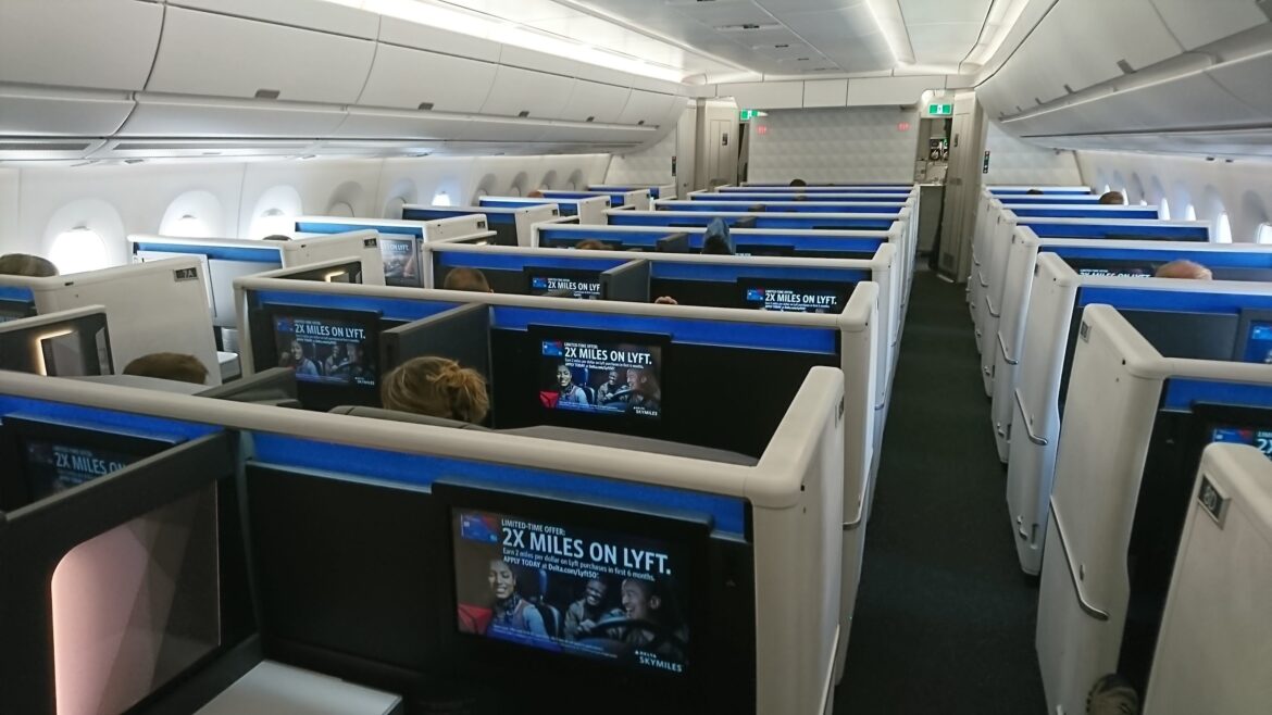 flying business class for the first time in a row of seats with monitors on the back