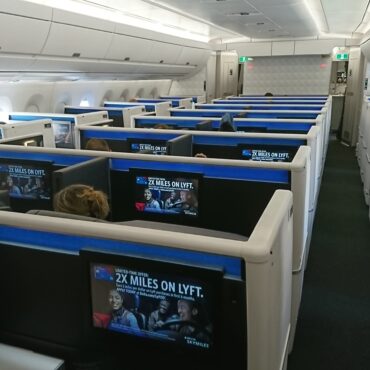 flying business class for the first time in a row of seats with monitors on the back