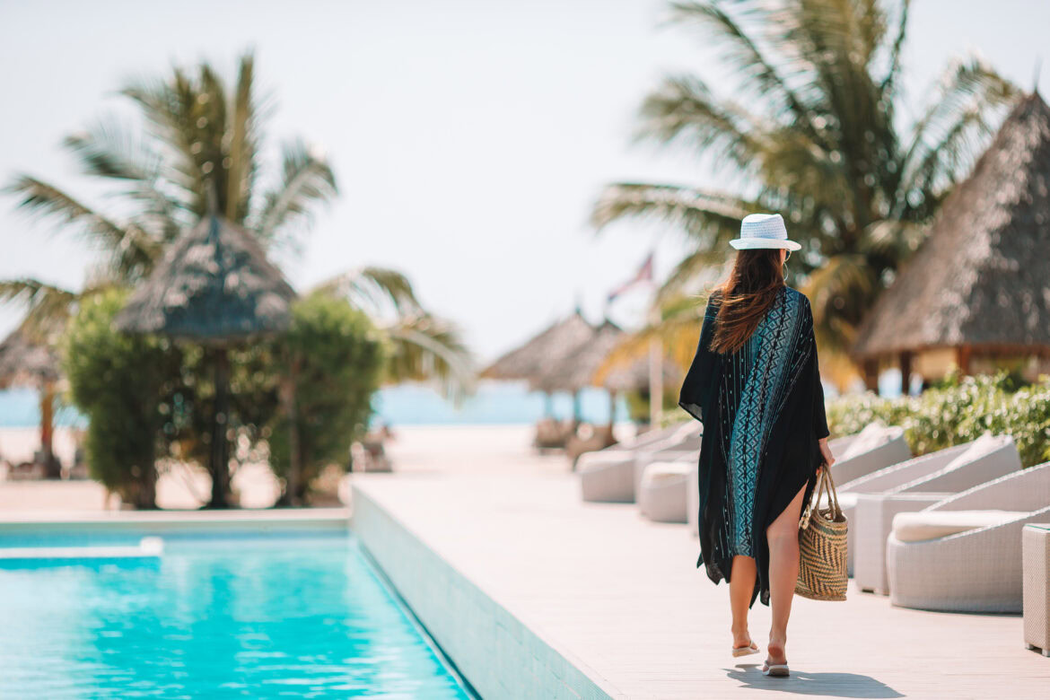 affordable luxury travel tips - woman walking past outdoor pool at resort