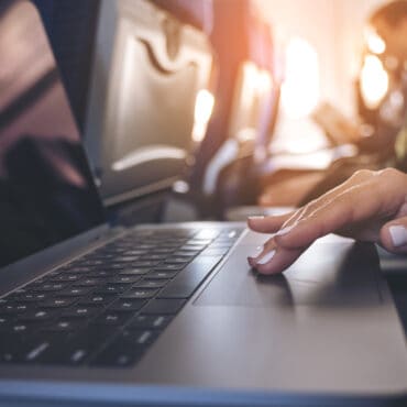 woman trying to avoid hidden airline fees for her next flight from the seat of her current flight